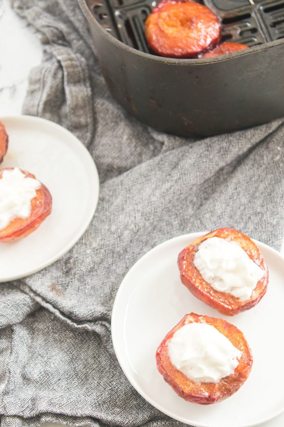 peaches on plates with air fryer with a few sliced peaches inside 