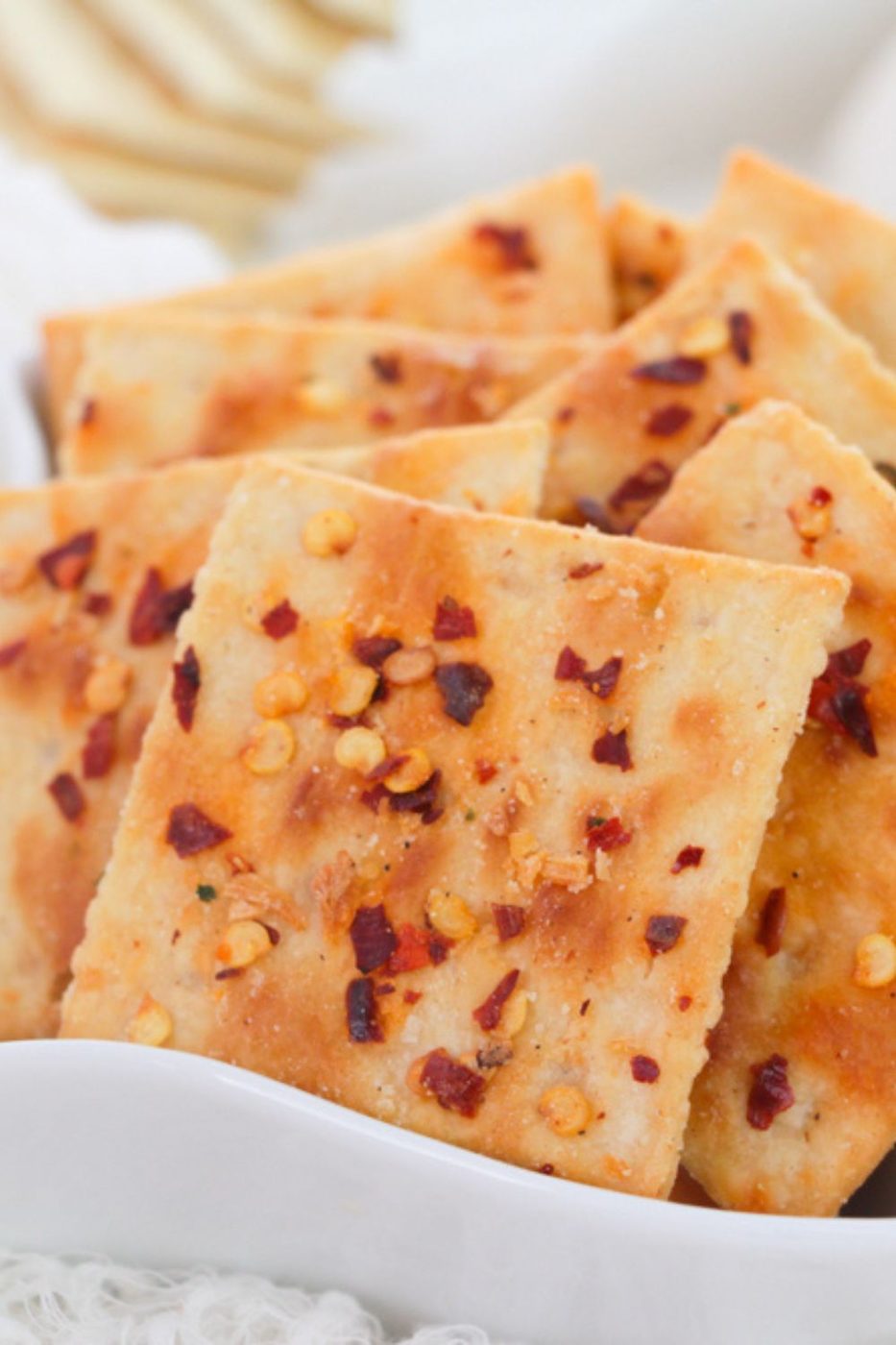 close up of red pepper flake coated saltine crackers in a white bowl 