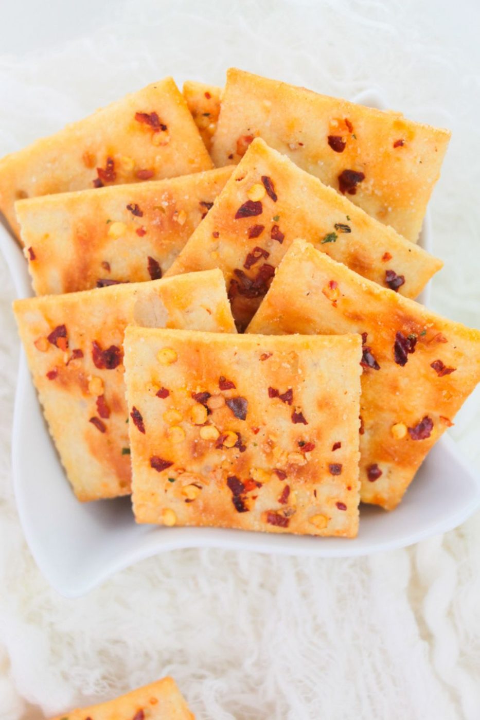 a handful of saltine fire crackers in a white bowl on a white table 