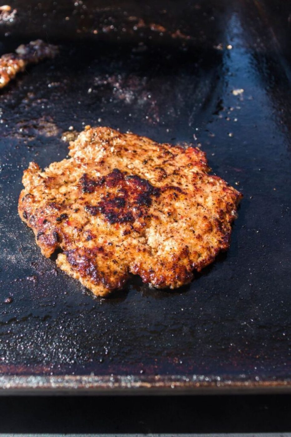 cooked sausage patty on a blackstone griddle 