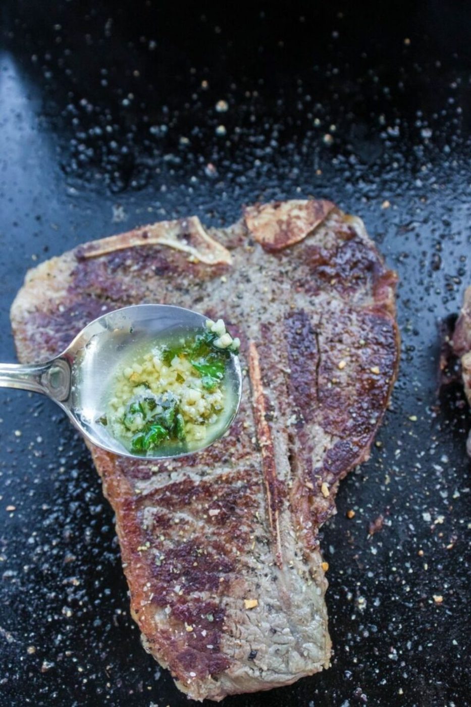 seared steak with a spoon of butter and garlic in spoon pouring onto steak