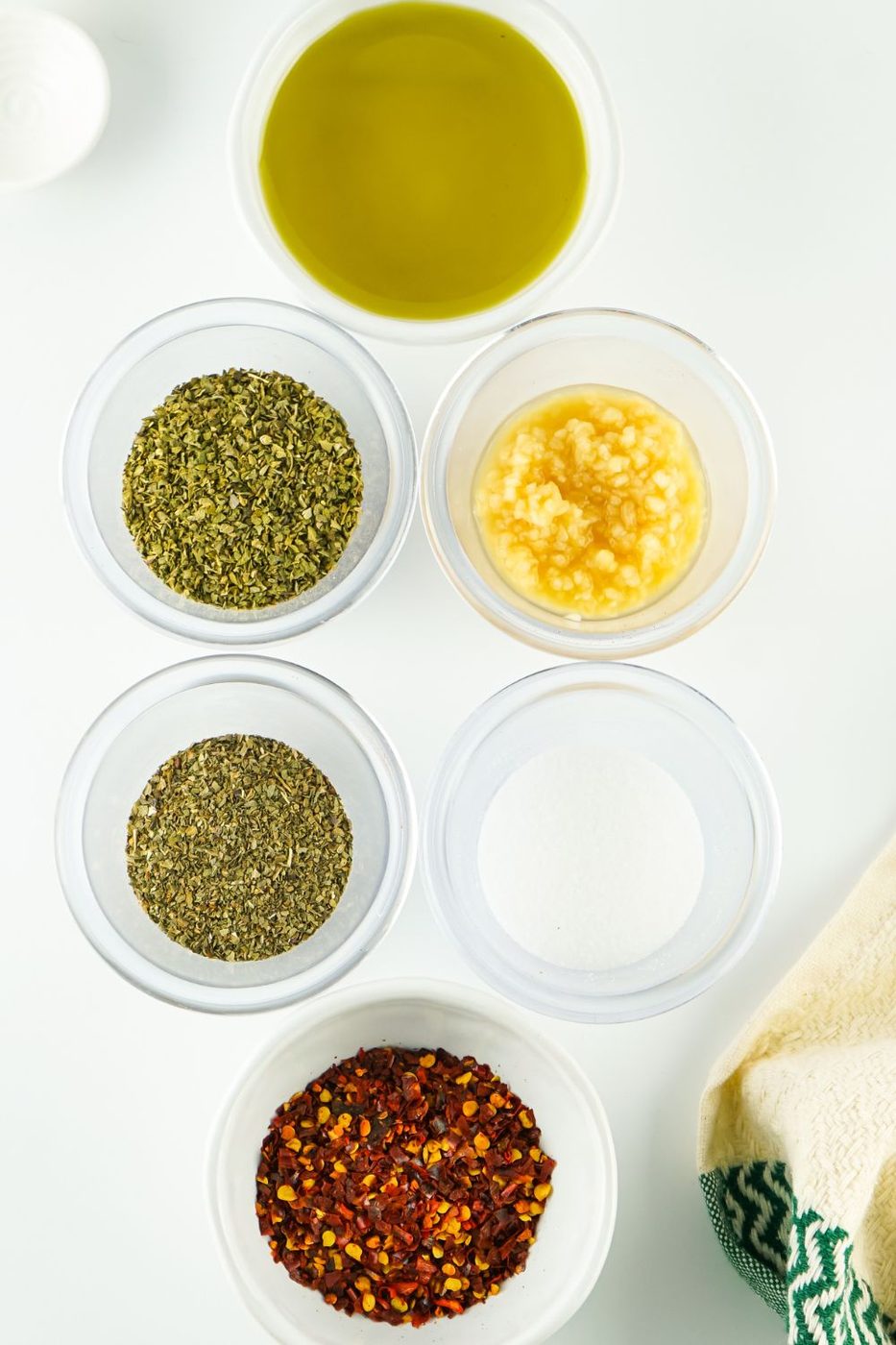 ingredients with fresh herbs and dried herbs in oil in glass bowls 