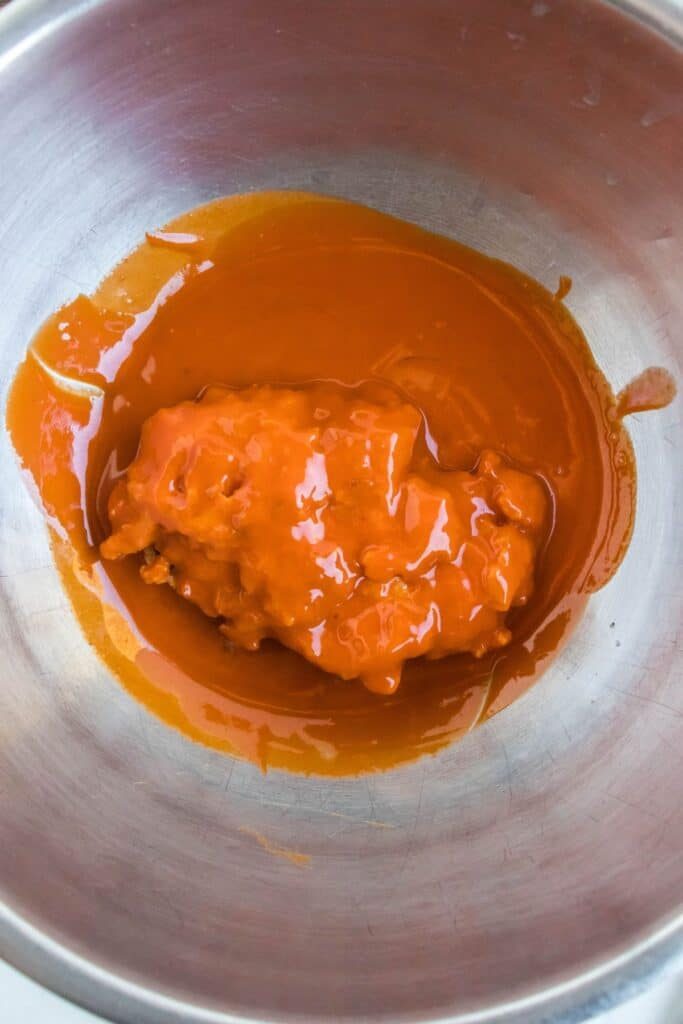 Buffalo Chicken tossed in a buffalo sauce in a metal pan 
