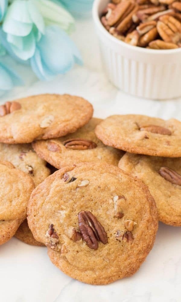 cookies stacked on top of each other on table with bowl of nuts behind it