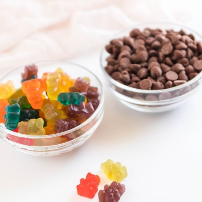 gummy bears and chocolate chips in glass bowls on table 