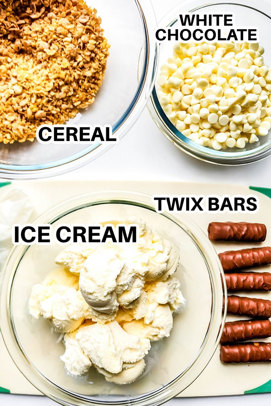 cornflaked crushed in a bowl, white chocolate chips in a bowl, twix candy bars on table and ice cream scooped in a bowl