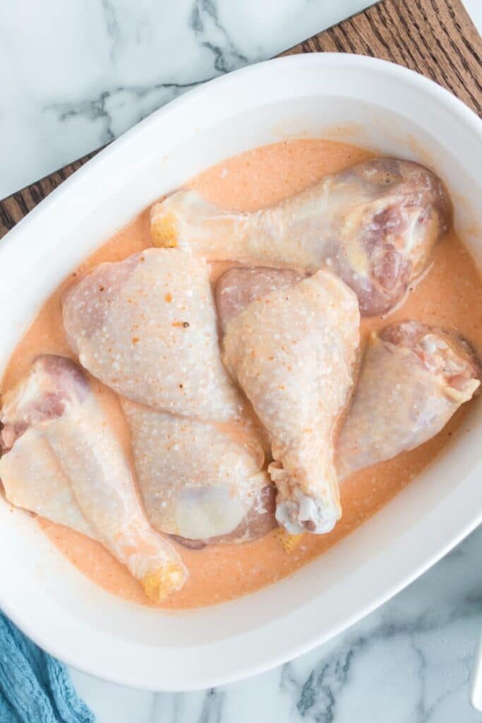 Fried Chicken Legs in a marinade in a pan on table 