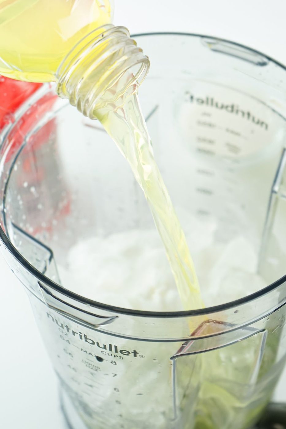 pouring gatorade into a mixer with ice in it 