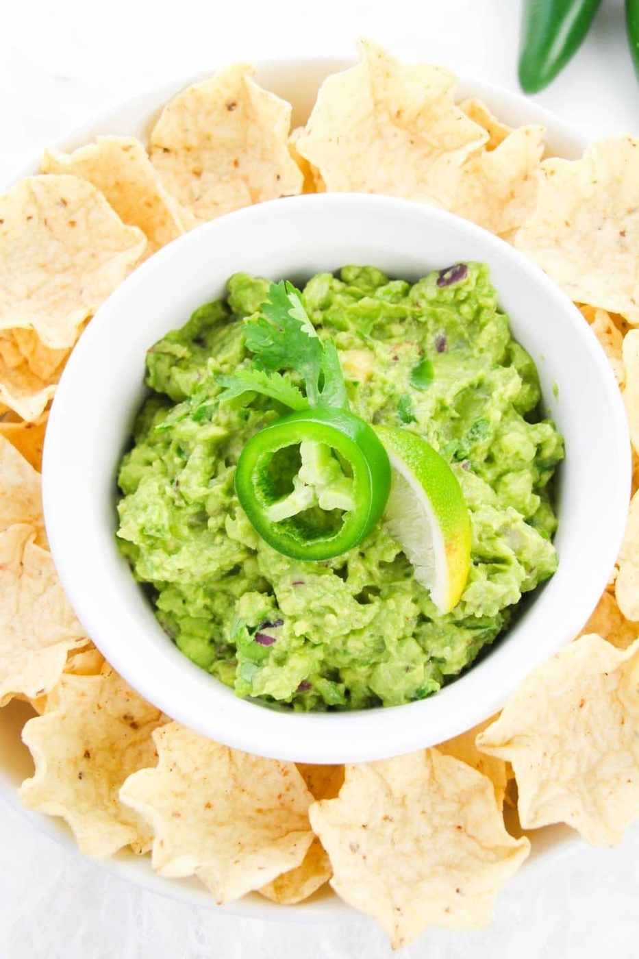 overhead shot of guacamole in bowl with chips around it 