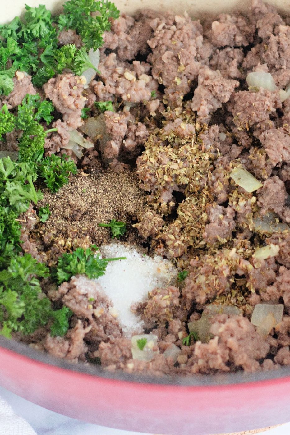 spices and fresh herbs in a pot with cooked meat 