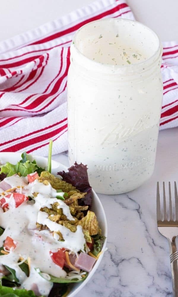 salad with dressing and mason jar of dressing beside it on table 