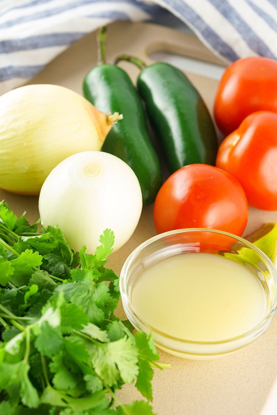 ingredients to make pico de gallo on table - jalapeno, tomatoes, onion, cilantro, lime juice