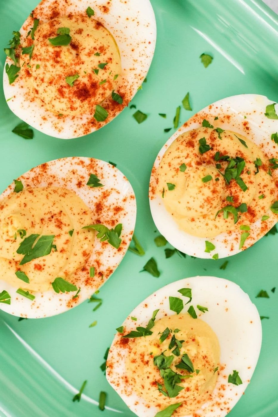 plate of hard boiled eggs filled with hummus and parsley
