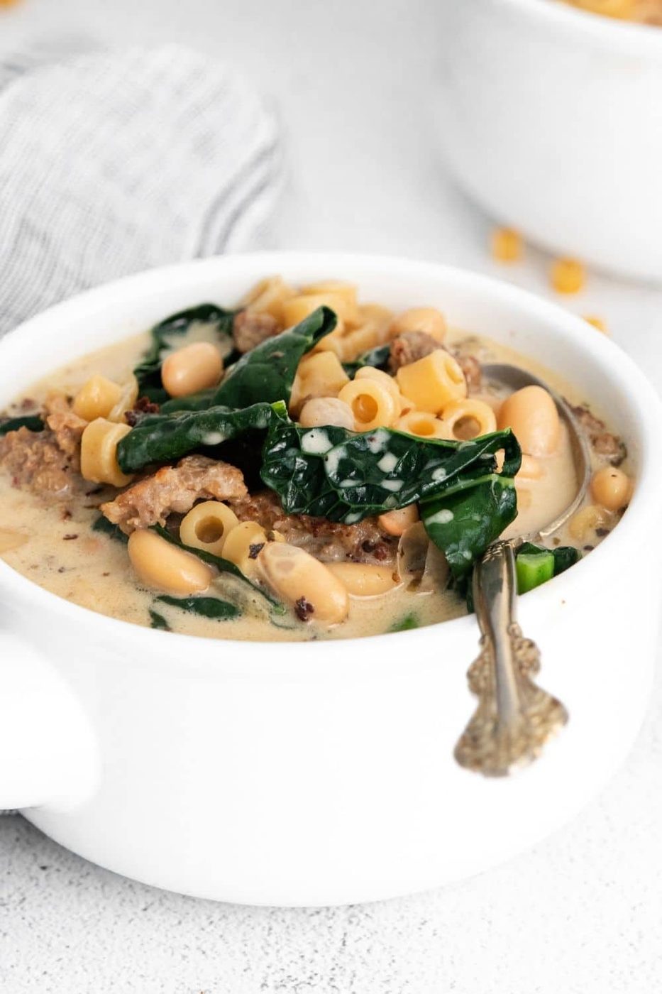 fagioli soup in a whote bowl with vintage spoon in it on counter 
