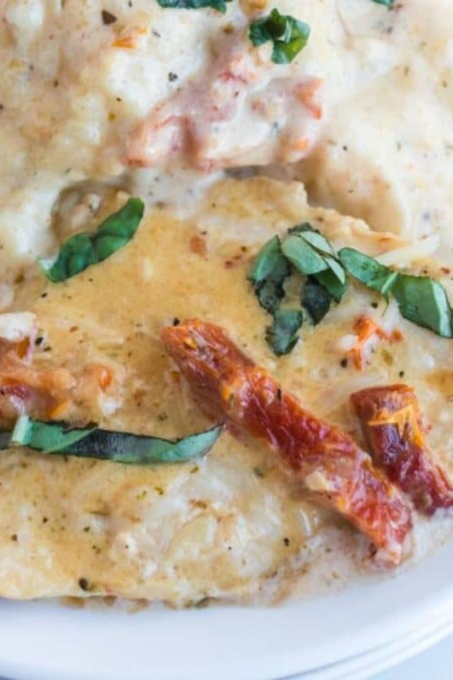 Marry Me Chicken on a plate with basil and sundried tomatoes on top of the chicken 