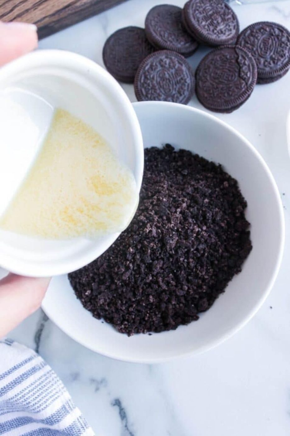 crushed cookies with butter pouring into bowl 