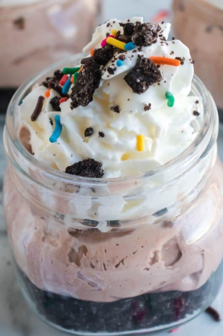 No Bake Oreo Cheesecake Jar with cookies and sprinkles on top of the whipped cream 