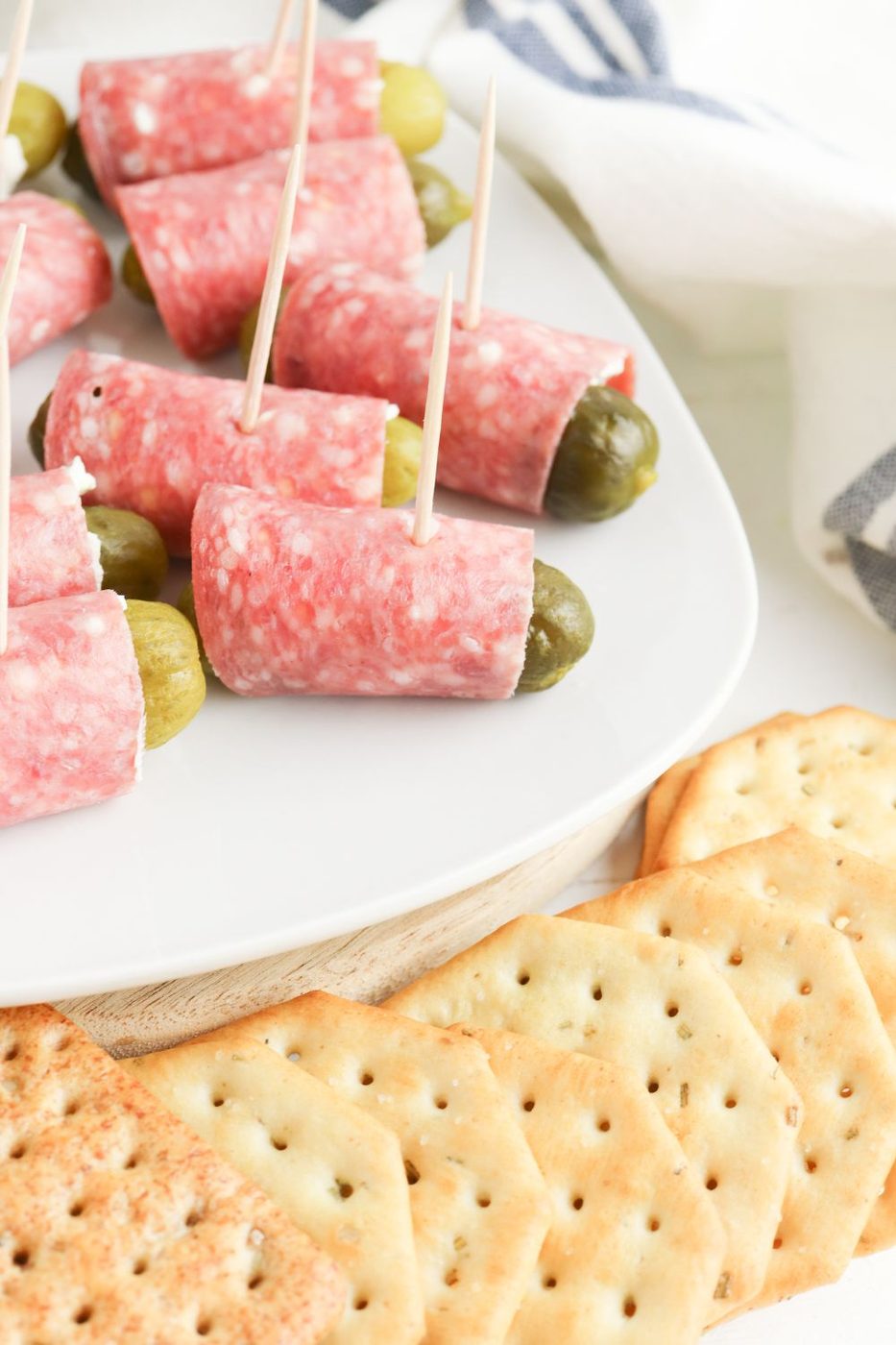 salami pickle wraps on plate with crackers around the plate 