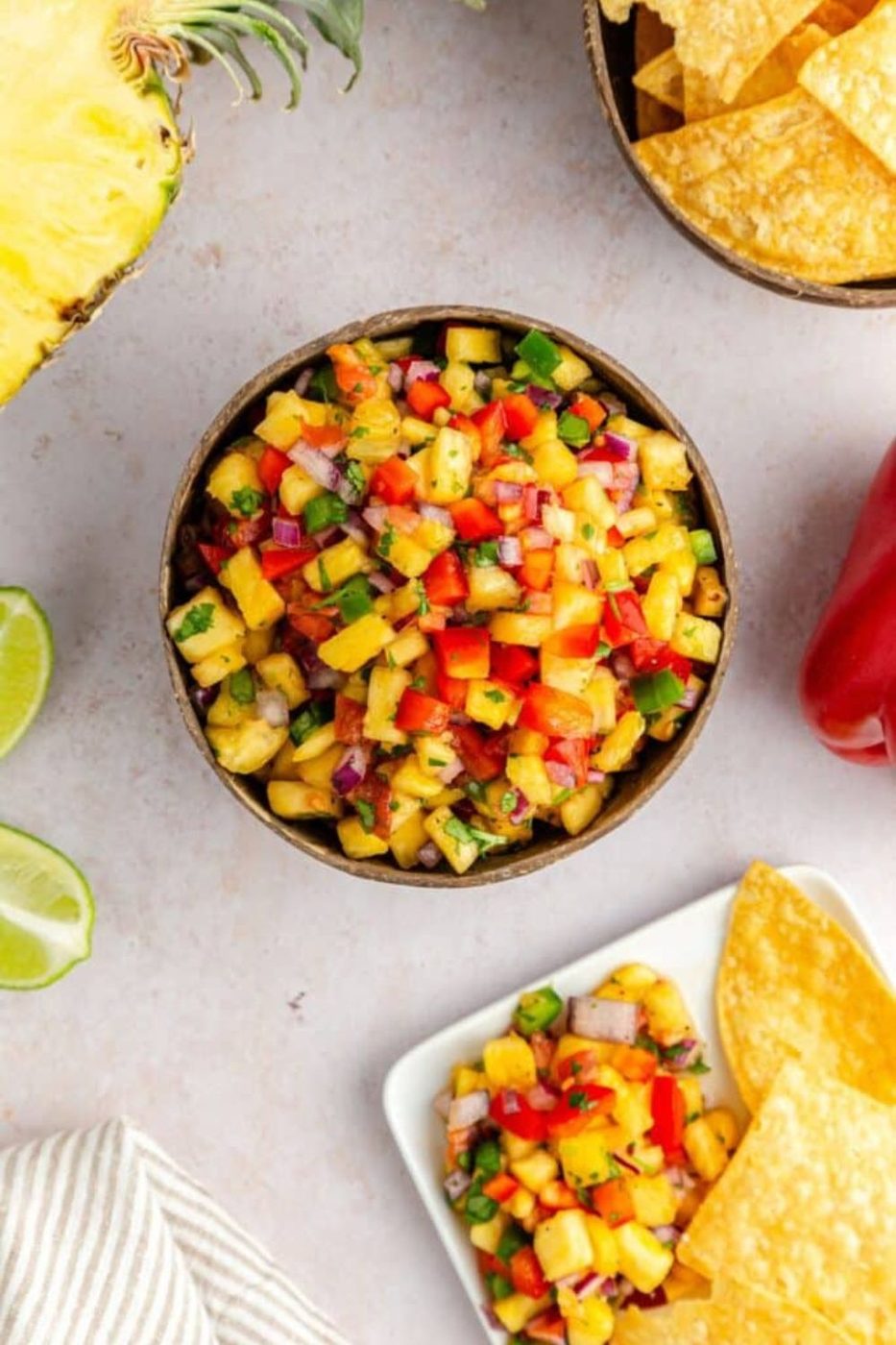 Pineapple Jalapeno Salsa in a bowl with a plate with more salsa on a plate with chips 