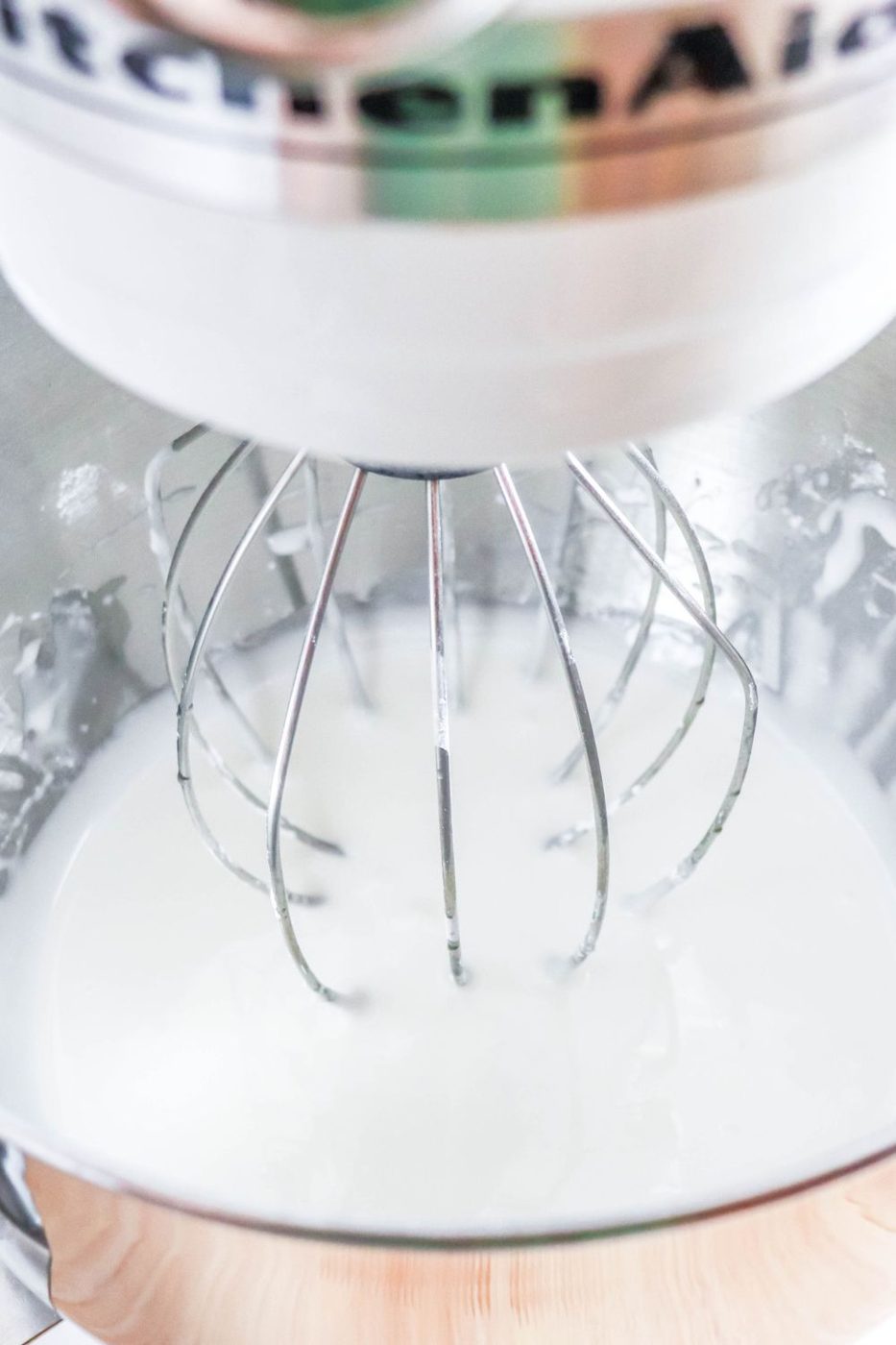 stand mixer with royal icing in it with whisk attachment 