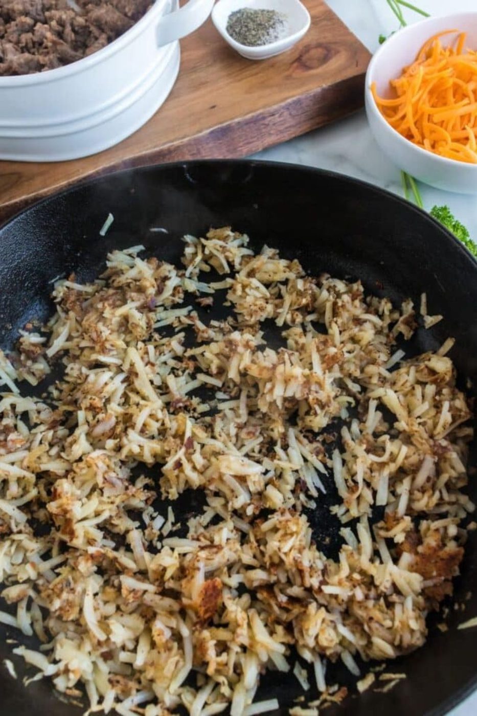 hashbrowns cooking in a cast iron skillet 