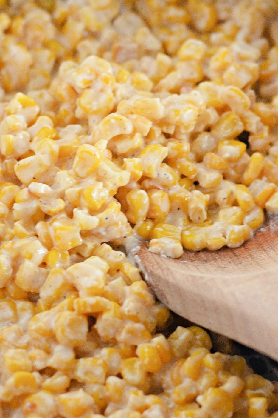 corn in a pan with a wooden spoon on the side of bowl 