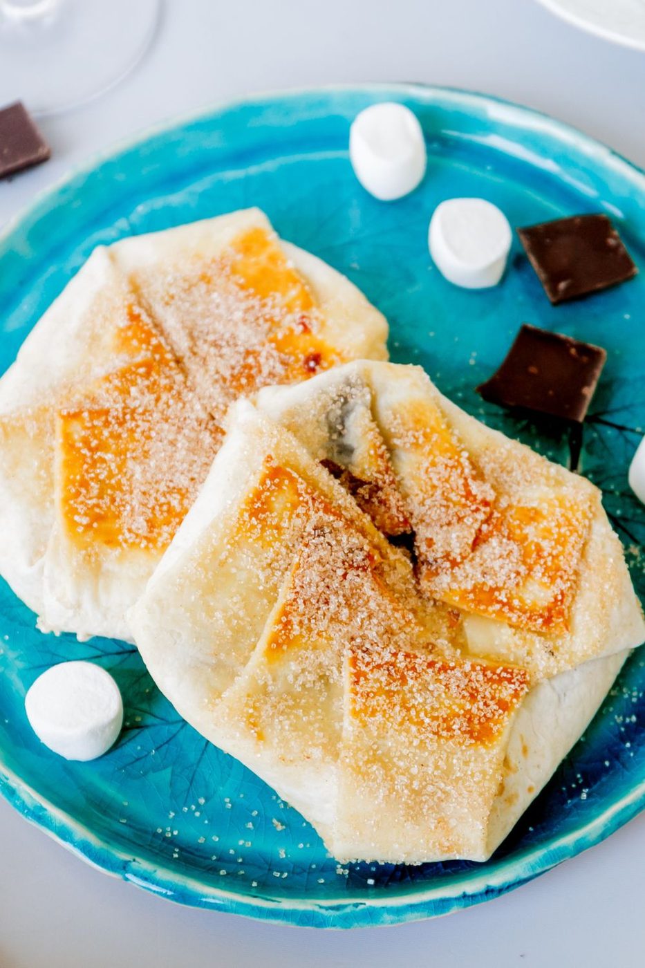 s'mores crunch wrap on blue plate with marshmallow and chocolate pieces on side of plate 