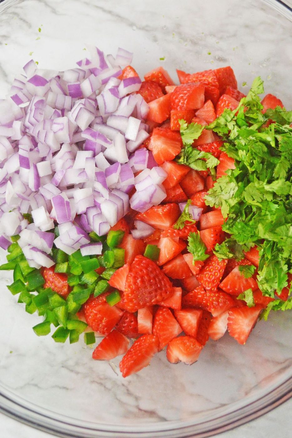 chopped strawberries, onion, jalapeno in a glass mixing bowl on table