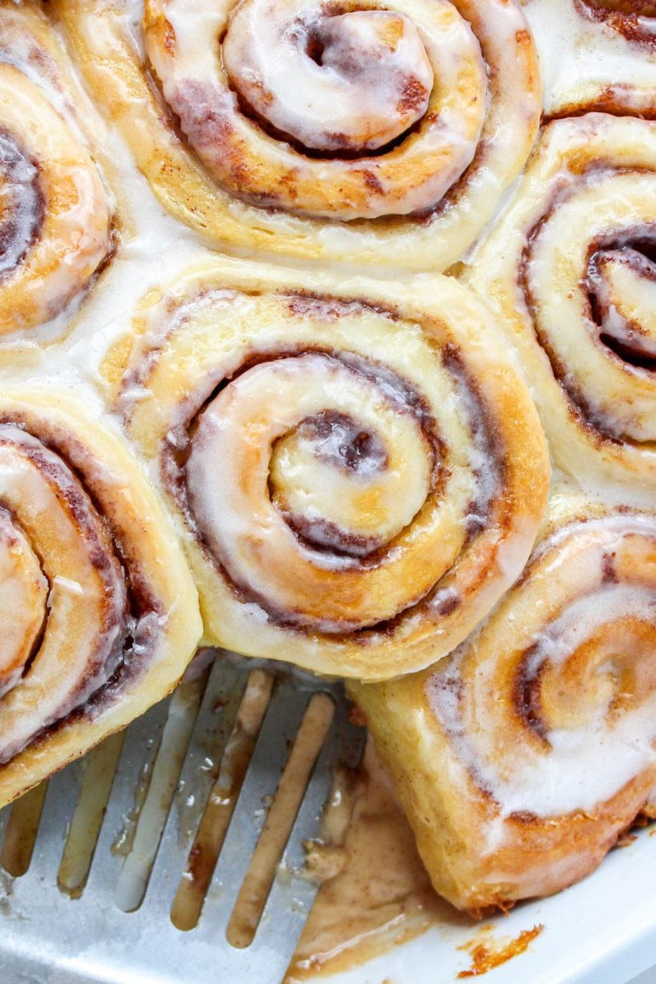 overhead shot of cinnamon rolls in pan with one roll moved 