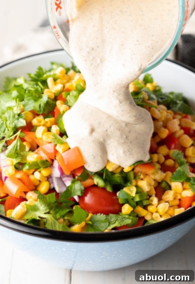 Creamy dressing poured over salad ingredients in a bowl.