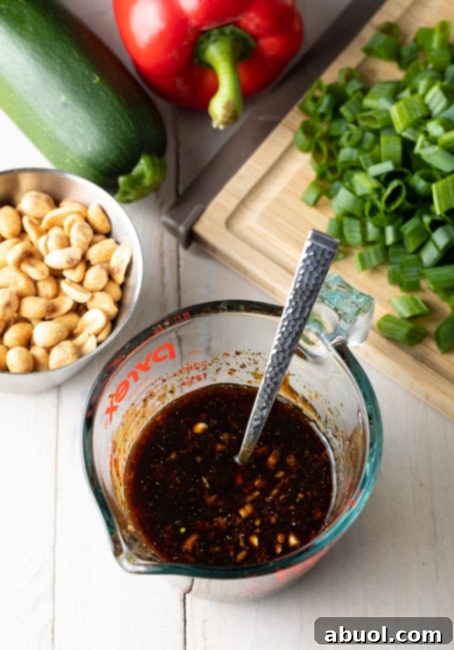 Glass measuring pitcher filled with a rich, dark stir-fry sauce, ready to be added to the wok.