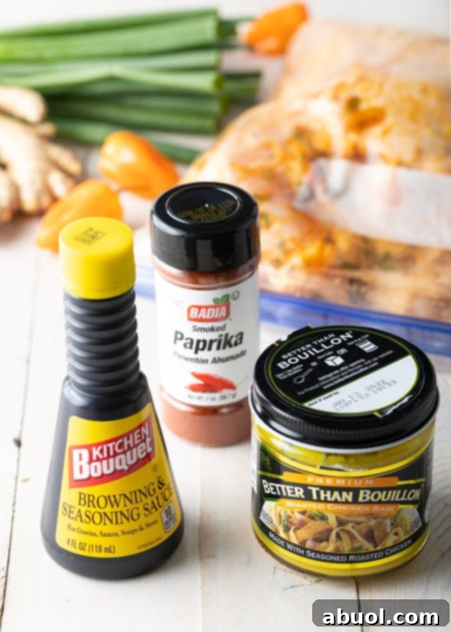 Assortment of fresh seasonings including scallions, habanero peppers, and ginger, arranged on a rustic wooden surface for brown stew chicken.