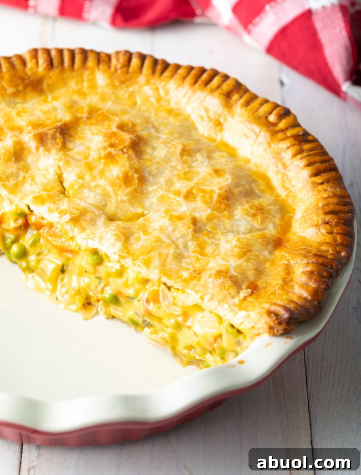 A half-eaten vegetarian pot pie in a baking dish, showcasing the rich, creamy vegetable filling peeking through the golden crust.