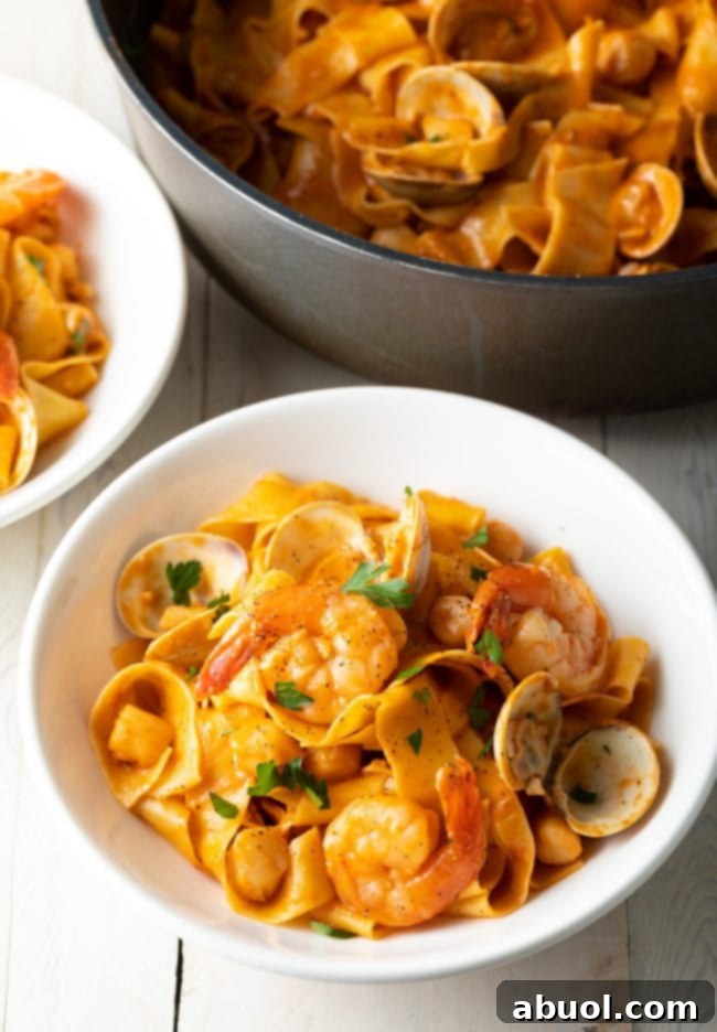 Serving of pappardelle pasta with seafood sauce in a white bowl.