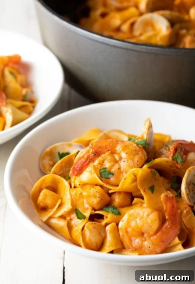 Serving of seafood pappardelle in a white bowl.