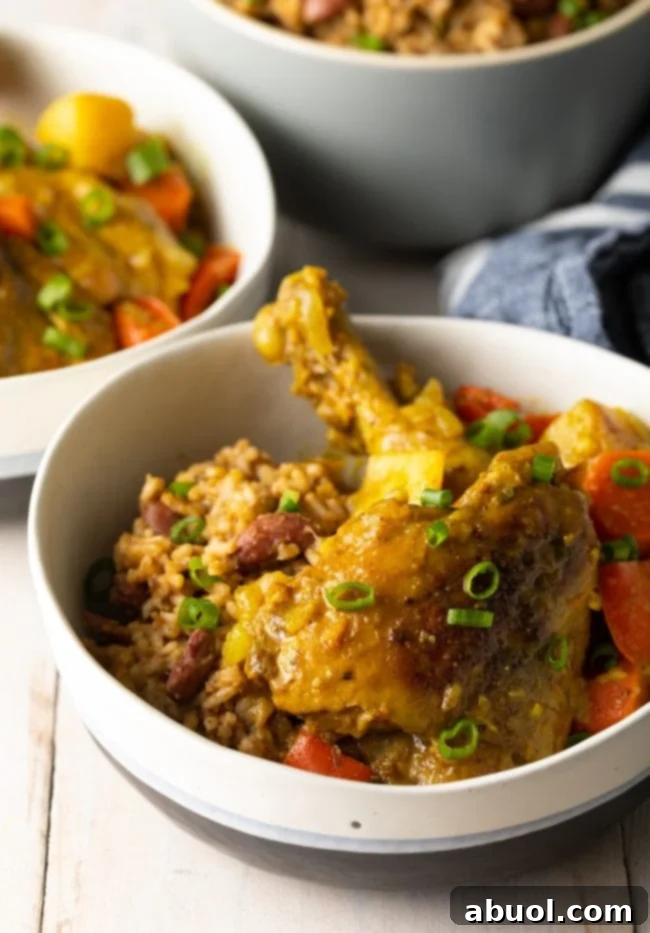 A close-up of Caribbean yellow curry chicken with rice and fresh scallions, garnished and ready to enjoy