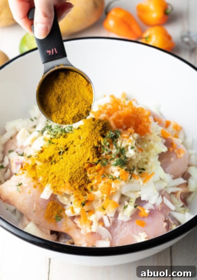 Marinated chicken pieces in a bowl, coated with yellow spices, onions, and herbs