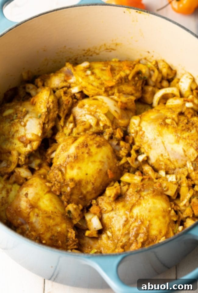 Browned chicken pieces mixed with onions and spices in a large pot, beginning to cook down