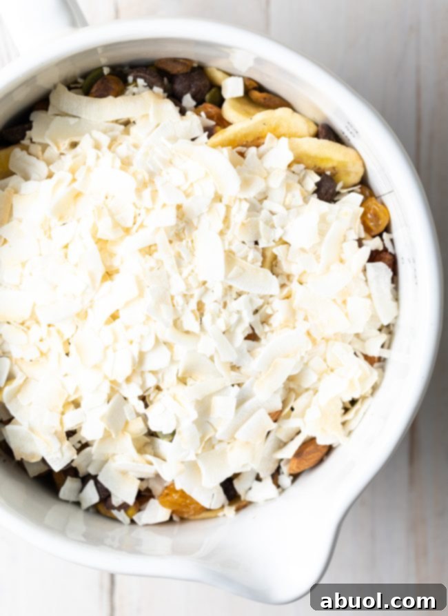 Healthy trail mix with a variety of nuts, seeds, and dried fruits in a white bowl.