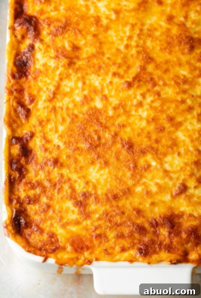 Top down view of cheesy pasitsio in a white baking dish.