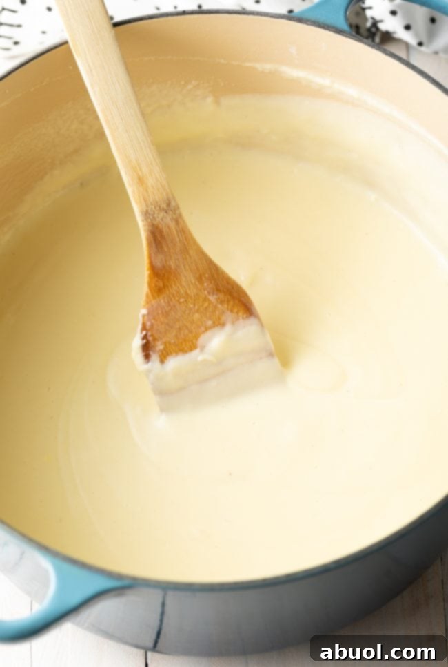 Stirring creamy bechamel sauce with a wooden spatula.