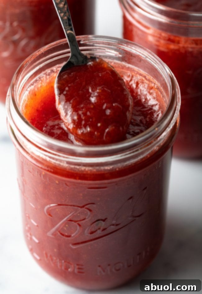 A glistening spoonful of homemade strawberry rhubarb jam, showcasing its thick, rich texture