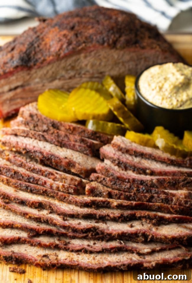 Dry-Brined Smoked Brisket 16 A beautifully presented sliced smoked beef brisket on a wooden cutting board, accompanied by an array of pickles and a ramekin of mustard, emphasizing its serving appeal.