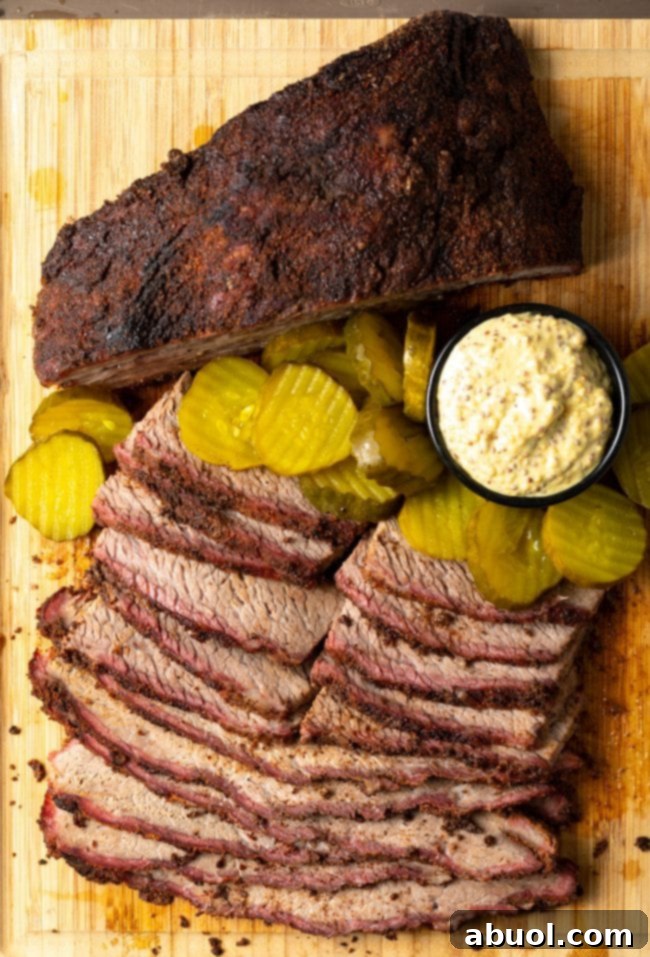 Dry-Brined Smoked Brisket 5 Slices of perfectly smoked dry brine brisket arranged on a wooden board, garnished with pickles and a dollop of mustard, ready for serving.