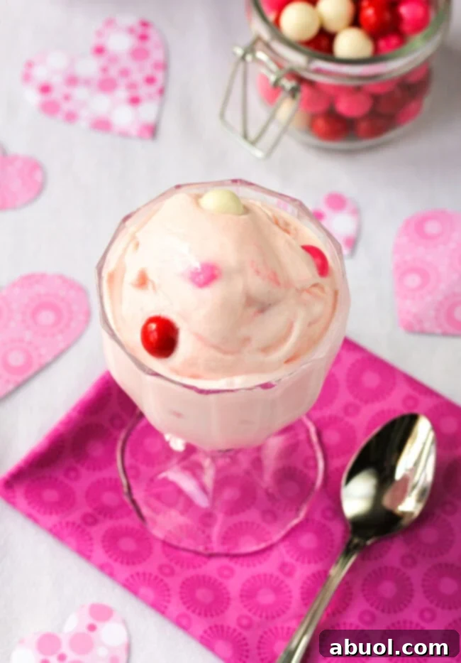 A top-down view of a sophisticated glass dish filled with vibrant Baskin Robbins-style bubblegum ice cream, highlighting its delightful pink hue and colorful gumball toppings.