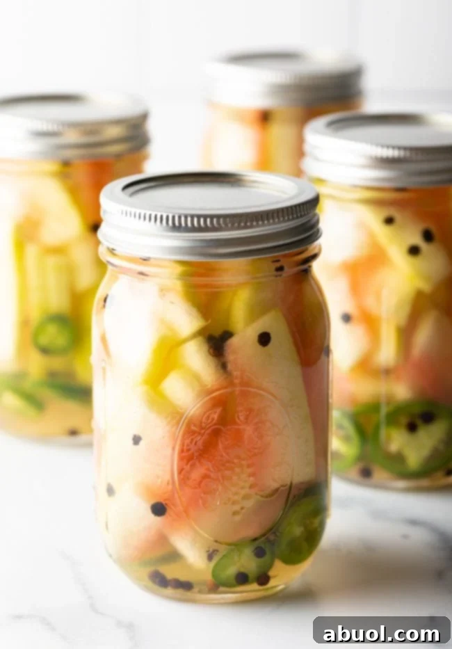 Pickled watermelon rinds in glass jars, showcasing their vibrant color and texture.