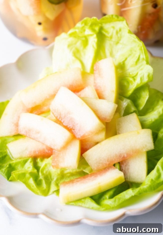 Close-up of pickled watermelon rinds arranged on a bed of fresh lettuce, ready to serve.