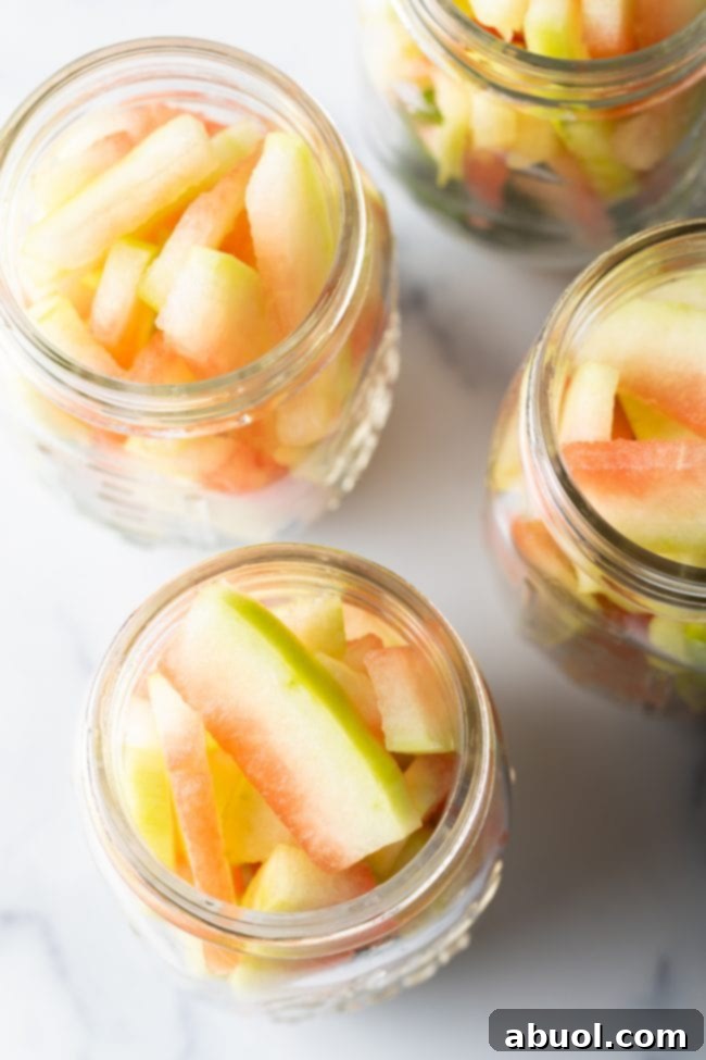 Jars being filled with tightly packed watermelon rind slices, ready for the pickling brine.