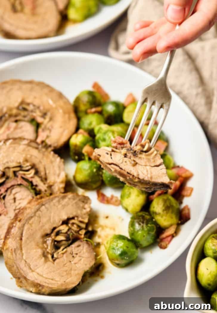Fork with a delicious piece of stuffed flank steak on it, showing the layers of filling.