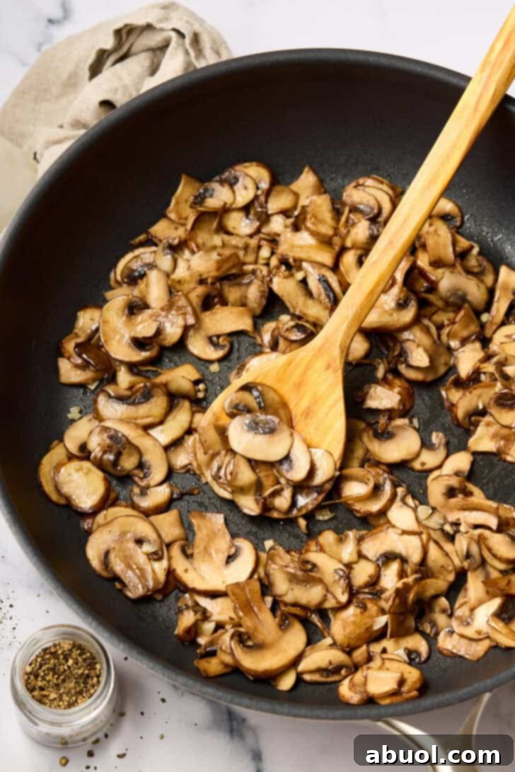 Wild mushrooms being sautéed in a skillet for the stuffed flank steak filling.